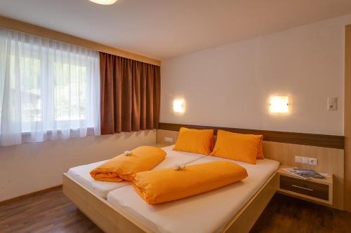 a bedroom with a bed with orange pillows on it at Apart Praxmarer in Sölden