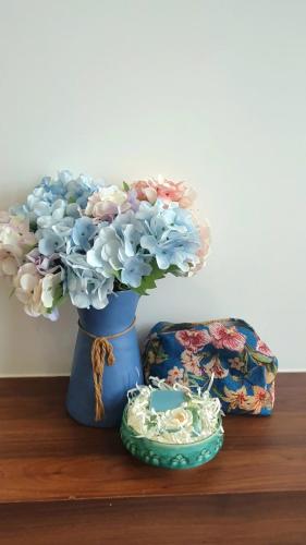 a blue vase with flowers in it on a table at Andi Homestay-Vinhomes Grand Park in Gò Công