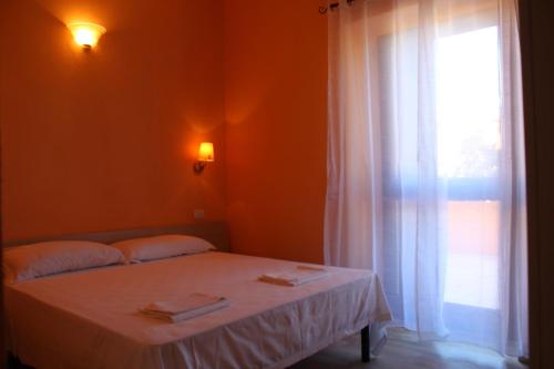 una camera da letto con un letto bianco con una finestra di B&B La Cantoniera a San Teodoro