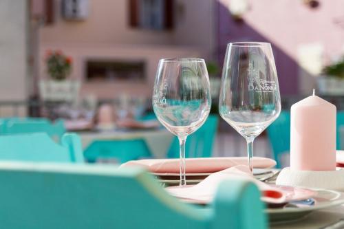two wine glasses sitting on a table with a candle at Heritage Hotel Chersin in Fažana
