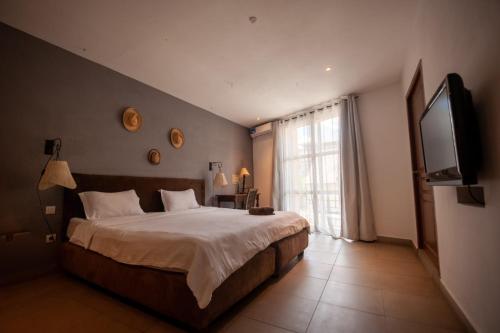 a bedroom with a large bed and a flat screen tv at Hôtel Restaurant La Ribaudière in Antananarivo