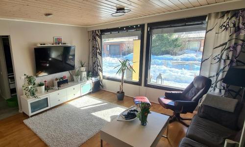 a living room with a television and a chair and a table at Viihtyisä ja kodikas omakotitalo isolla pihalla in Lohja