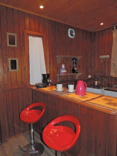 a kitchen with two red stools in a room at Cabana Verde Rosa in Barra de Ibiraquera