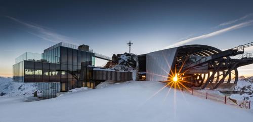 a building in the snow with the sun shining on it at Apart Praxmarer in Sölden