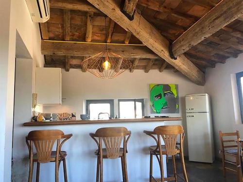 Il comprend une cuisine équipée d'un bar avec des chaises et un réfrigérateur. dans l'établissement L'inattendu - Chambre d'Hôte vue exceptionnelle chez Renato, à Uzès
