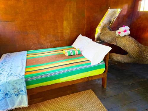 a small bed with a colorful blanket and a stuffed elephant at Yala Wild Tree House in Hambantota
