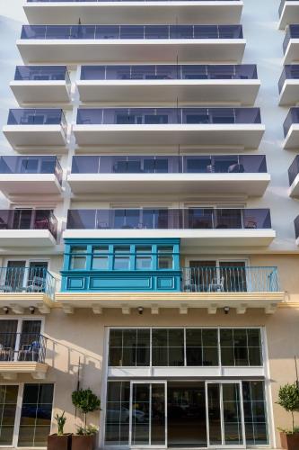 an apartment building with a blue balcony at Novotel Malta Sliema in Il-Gżira