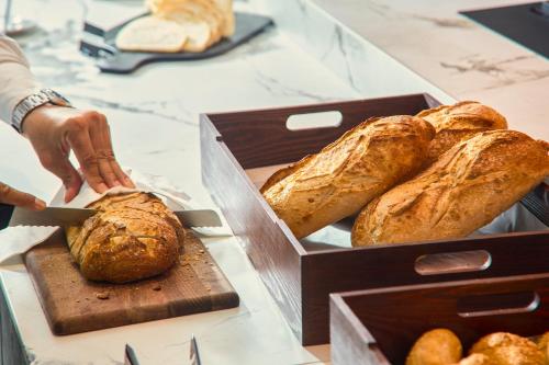 a person is reaching into a box of bread at Novotel Malta Sliema in Il-Gżira