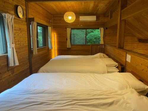 a bedroom with two beds in a log cabin at Komore Villa Kita-Karuizawa こもれヴィラ北軽井沢 in Tsumagoi