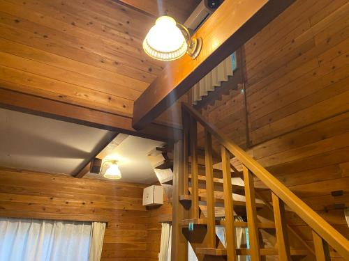 a staircase in a room with wooden walls and ceilings at Komore Villa Kita-Karuizawa こもれヴィラ北軽井沢 in Tsumagoi