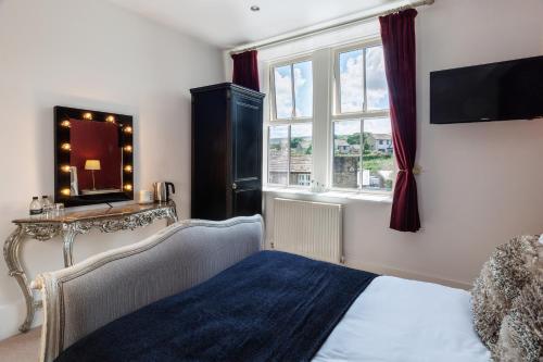 a bedroom with a bed and a mirror and a window at The Craven Heifer in Addingham