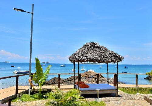 a bed under a straw umbrella on a beach at Hôtel de rêve Nosy Komba in Nosy Komba