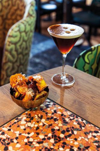 a drink and a bowl of food on a table at Radisson Collection The National Hotel, Brussels in Zaventem
