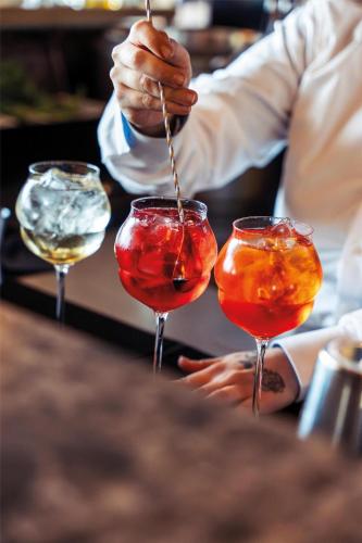 a bartender is preparing three cocktails in wine glasses at Radisson Collection The National Hotel, Brussels in Zaventem