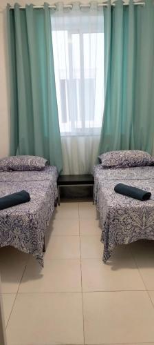 アリカンテにあるPensión La Marinaの緑のカーテンがかかった部屋にベッドが2つ