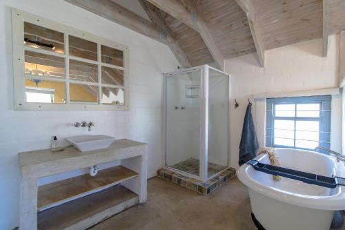a bathroom with a tub and a sink and a toilet at Milky Way Holiday Home in Paternoster