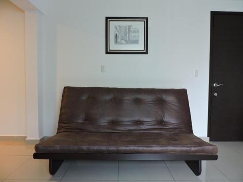 a brown leather couch sitting against a white wall at Suites Hamburgo in Mexico City