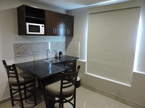 a kitchen with a black table with chairs and a microwave at Suites Hamburgo in Mexico City