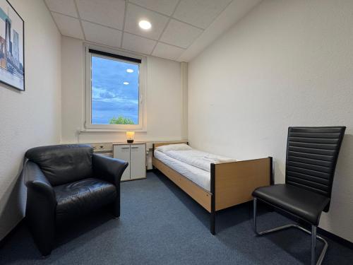 a room with a bed and a chair and a window at Thuja Apartments Karlsruhe-Neureut by KurzZeit in Karlsruhe