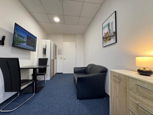 an office with a chair and a desk and a tv at Thuja Apartments Karlsruhe-Neureut by KurzZeit in Karlsruhe