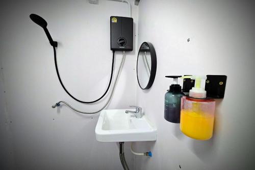 a bathroom with a sink and a phone on the wall at Kua Car Camp in Lampang