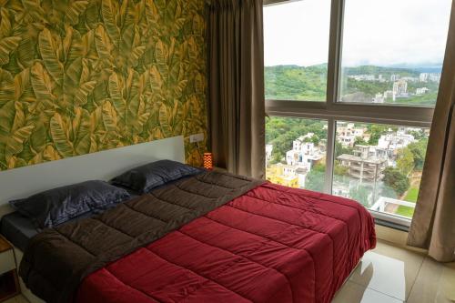 a bedroom with a red bed and a large window at Anandam Luxury Hill View 1BHK in Pune in Pune