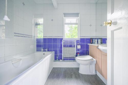 a bathroom with a tub and a toilet and a sink at Charming Family-Friendly 3-Bedroom House with Parking & Spacious Garden in Milton