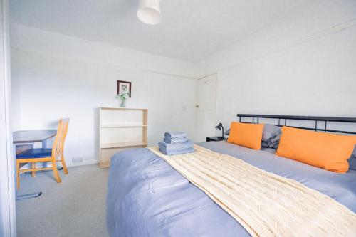 a bedroom with a bed with orange pillows and a desk at Charming Family-Friendly 3-Bedroom House with Parking & Spacious Garden in Milton