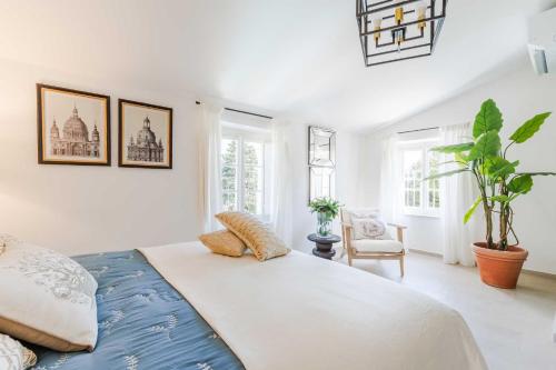 a white bedroom with a large bed and a chair at Villa Podere Falcione in San Quirico di Moriano