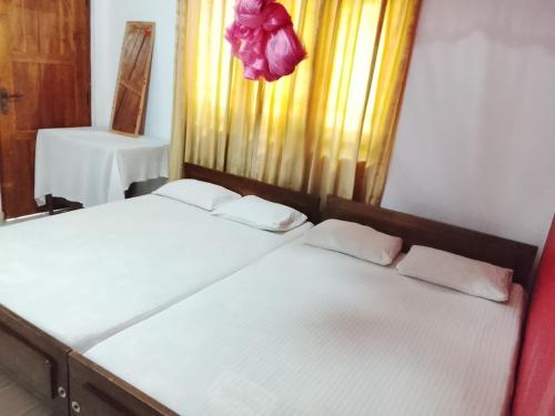 two twin beds in a room with a window at Ranmini Family Resort in Anuradhapura