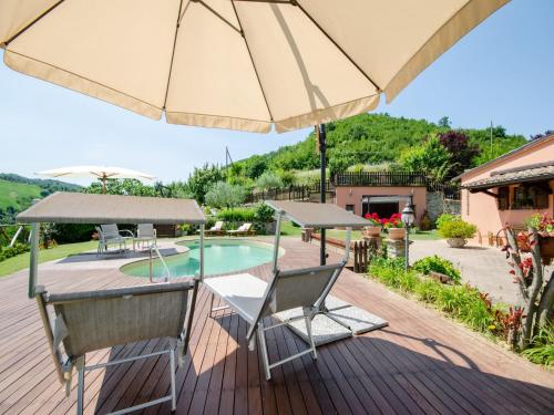 a deck with an umbrella and chairs and a pool at Pet-Friendly Villa with Pool in Urbino