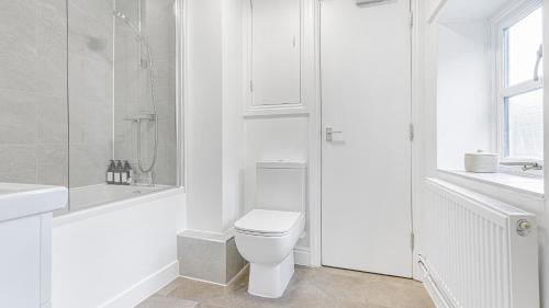 a white bathroom with a toilet and a shower at Newly renovated 2-bed house in Lechlade with parking in Lechlade