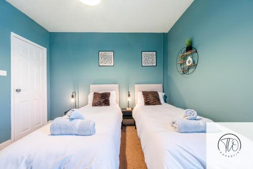 Dos camas en una habitación con paredes azules. en 2BR House -Centrally Located, en Ipswich
