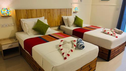 two beds in a hotel room with dolls on them at Dream Inn at Thulusdhoo in Thulusdhoo