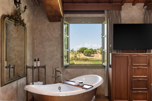 a bathroom with a tub and a large window at Villa Petriolo - Small Luxury Hotels of the World in Cerreto Guidi