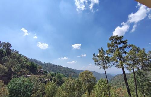 a view of a mountain with trees and a blue sky at TreeHouse Kasauli Operated By Splendid Hotels I Vacations I Family Groups & Events I Forest Treks I Memories I in Kasauli