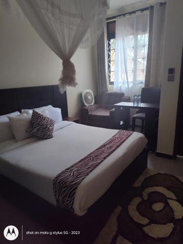 una camera da letto con un letto, una sedia e una finestra di Sonkoyaz bed and breakfast a Entebbe