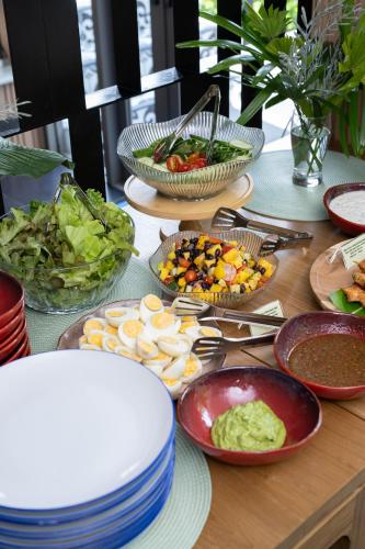 a table with plates of food and bowls of food at Elite Atoll Serviced Apartments Phuket in Rawai Beach
