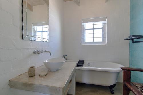 a bathroom with a tub and a sink and a mirror at Die Veldmuis in Paternoster