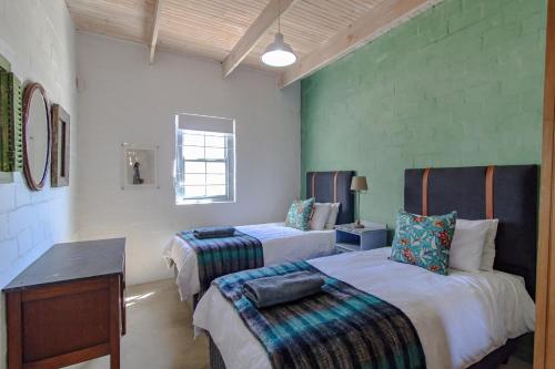 a bedroom with two beds and a table and a desk at Die Veldmuis in Paternoster