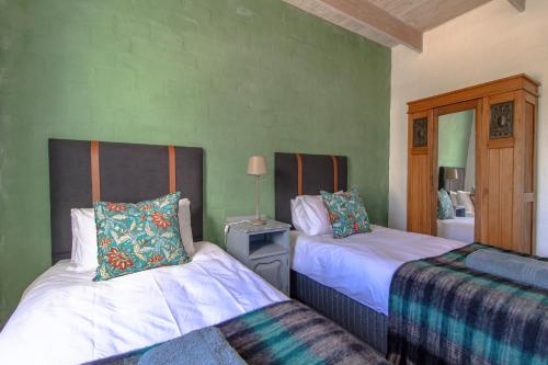 two beds in a room with green walls at Die Veldmuis in Paternoster