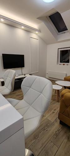 a white living room with a couch and a tv at MJ apartments in Vršac