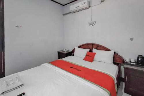 a bedroom with a bed with a red blanket at RedDoorz Syariah at Hotel Adi Sederhana near Stasiun Jatibarang in Sleman