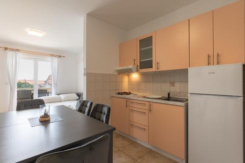 a kitchen with a table and a white refrigerator at Villa Royal 2 with a pool in Novalja