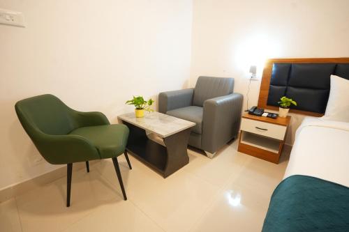 a room with two chairs and a bed and a table at Elite Hotel HITECH in Hyderabad