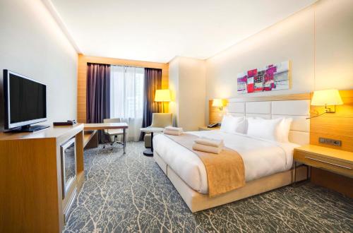 a hotel room with a large bed and a flat screen tv at Holiday Inn Baku by IHG in Baku