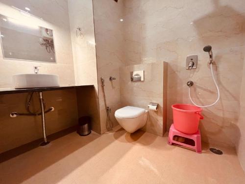 a bathroom with a toilet and a shower and a pink stool at Ganges Blossom Luxury Stay in Haridwār