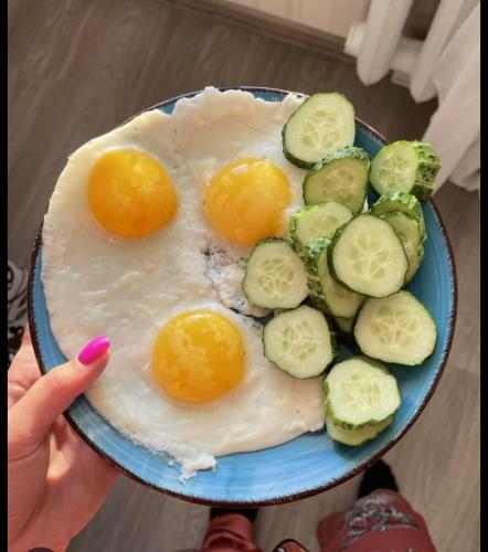 una persona sosteniendo un plato azul con huevos y verduras en IVA guest House, en Karakol