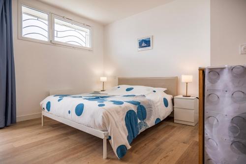 a white bedroom with a bed and two windows at Les balcons de la Thalasso in Roscoff
