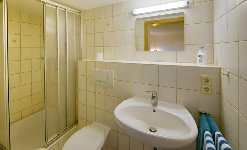 a white bathroom with a sink and a shower at Gasthaus-pension zum Löwen in Grafenhausen